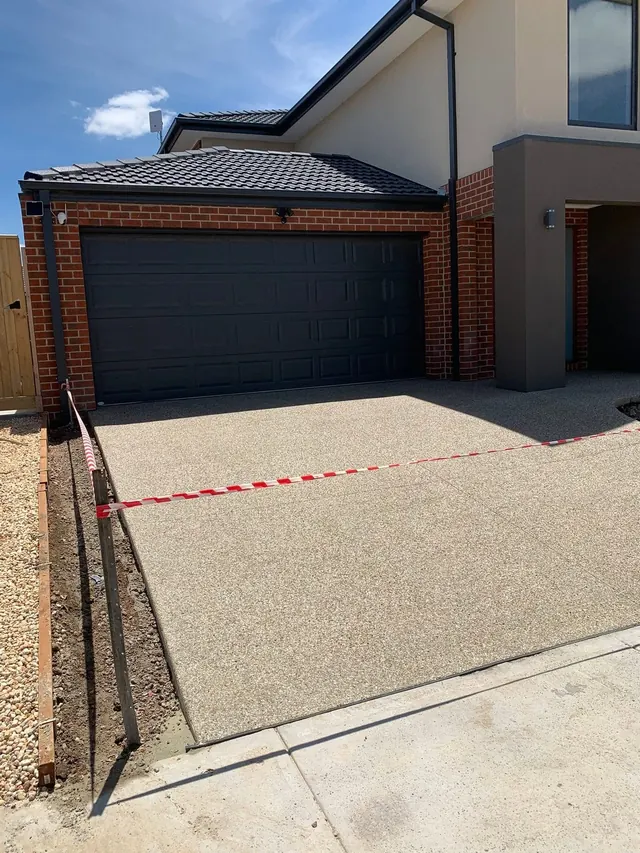 Charcoal exposed aggregate driveway in front of a modern home